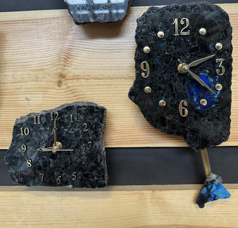 Kaksi erilaista kivestä valmistettua seinäkelloa